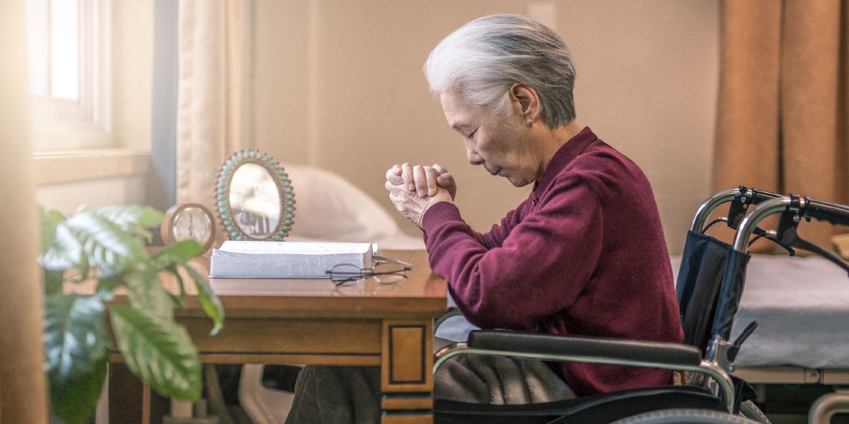 一個坐輪椅嘅年長姊妹喺度禱告