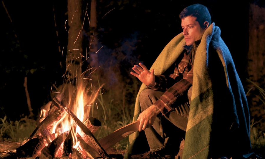 A man warms himself by a fire