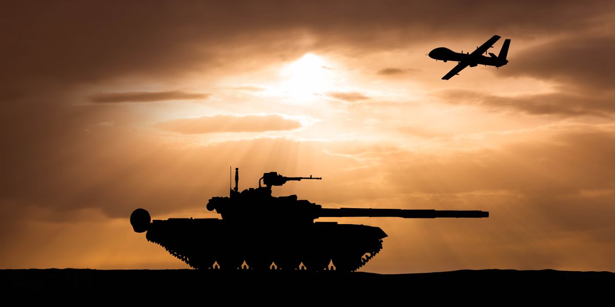 A military tank and a combat drone silhouetted against a sunset.
