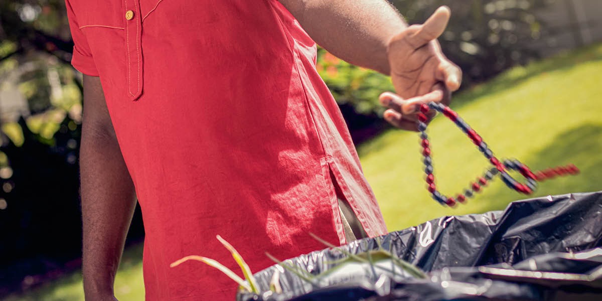 A man throwing away a beaded necklace related to spiritism.