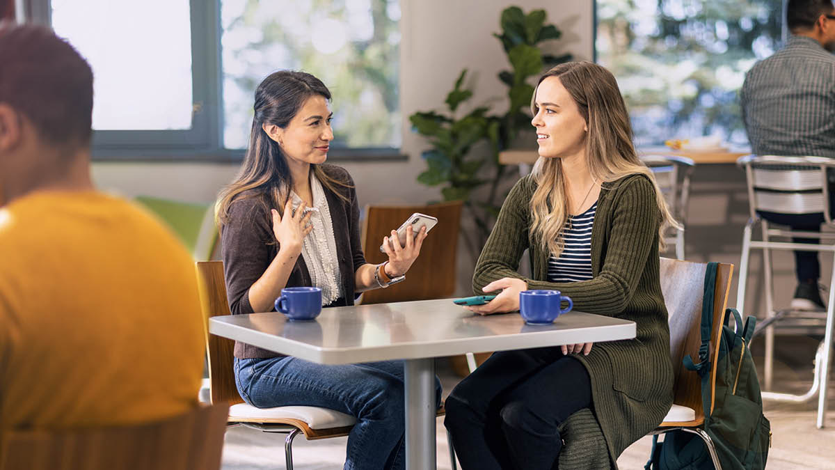 A sister witnessing to a woman at a café.